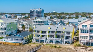 A coastal residential area with multi-story houses featuring balconies and a wooden boardwalk.