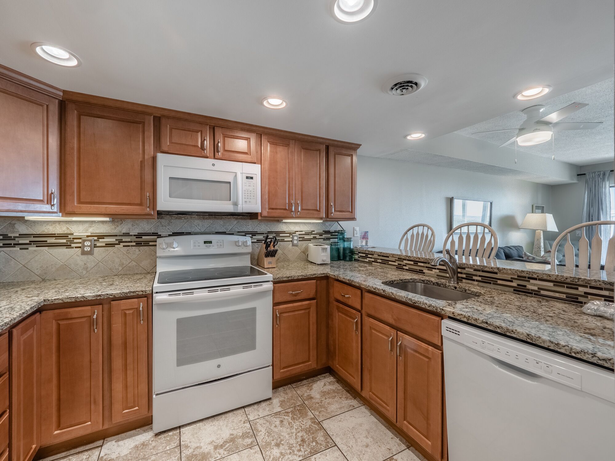 A modern kitchen with wooden cabinets, a built-in microwave, a stove, and a dishwasher.