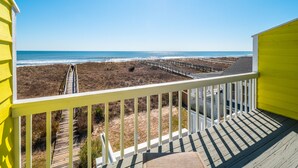 A balcony with a view of a beach and a boardwalk.