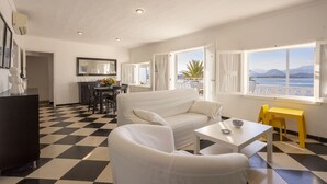 Une pièce avec un sol à carreaux, un canapé blanc, une petite table et une chaise jaune.
