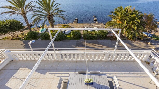 Une terrasse offrant une vue sur un lac, des palmiers et une balustrade blanche.
