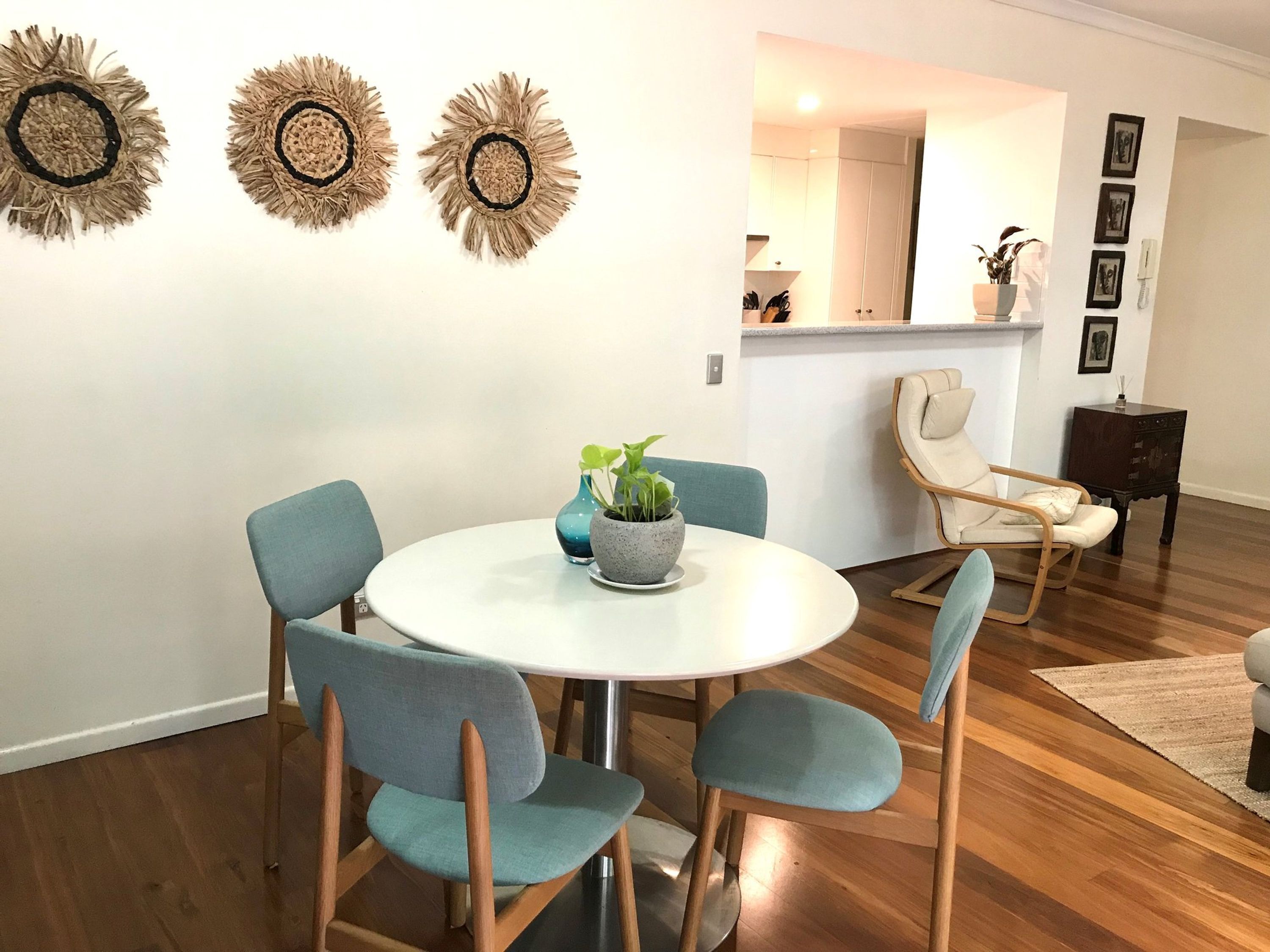A dining area with a round table, four chairs, and two potted plants.