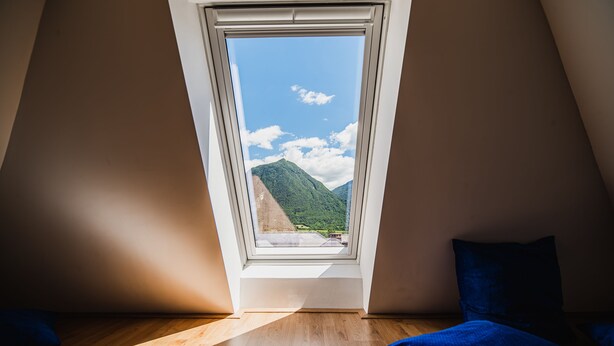 Ein Zimmer mit Dachfenster, Holzboden und blauer Bettwäsche.