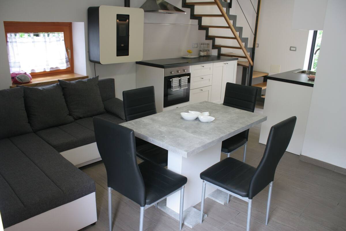 A modern kitchen with a dining area, built-in oven, and a staircase leading to another level.