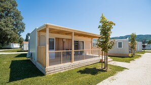 Een gelijkvloerse stacaravan met een veranda, een klein terras en een raam.