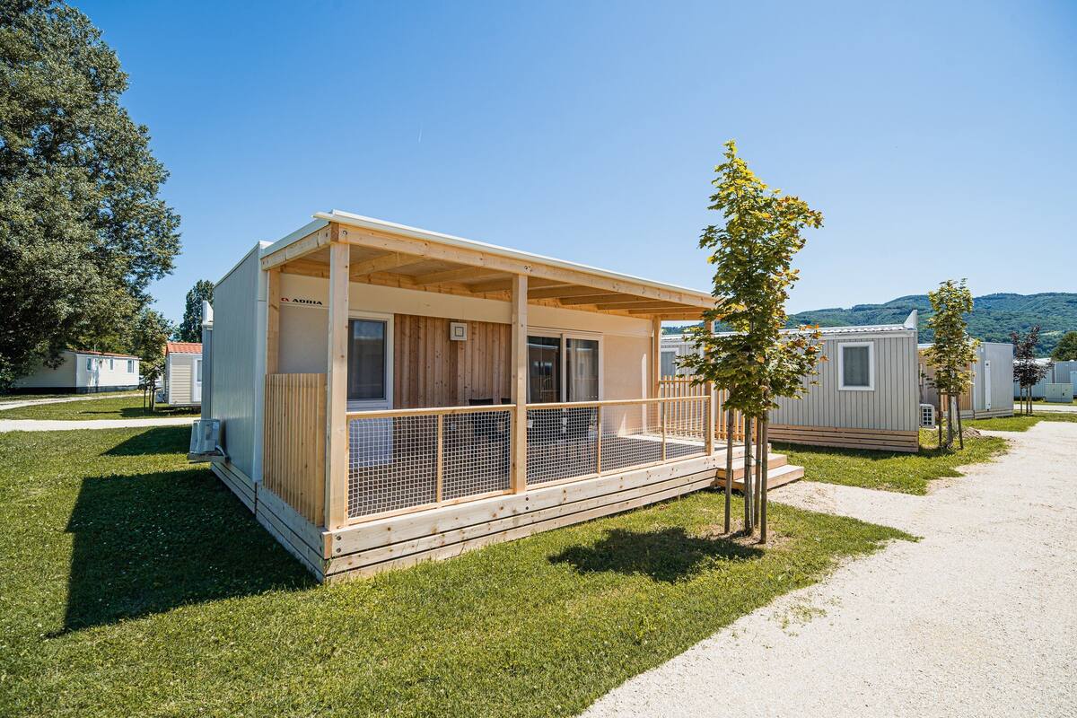 Een gelijkvloerse stacaravan met een veranda, een klein terras en een raam.