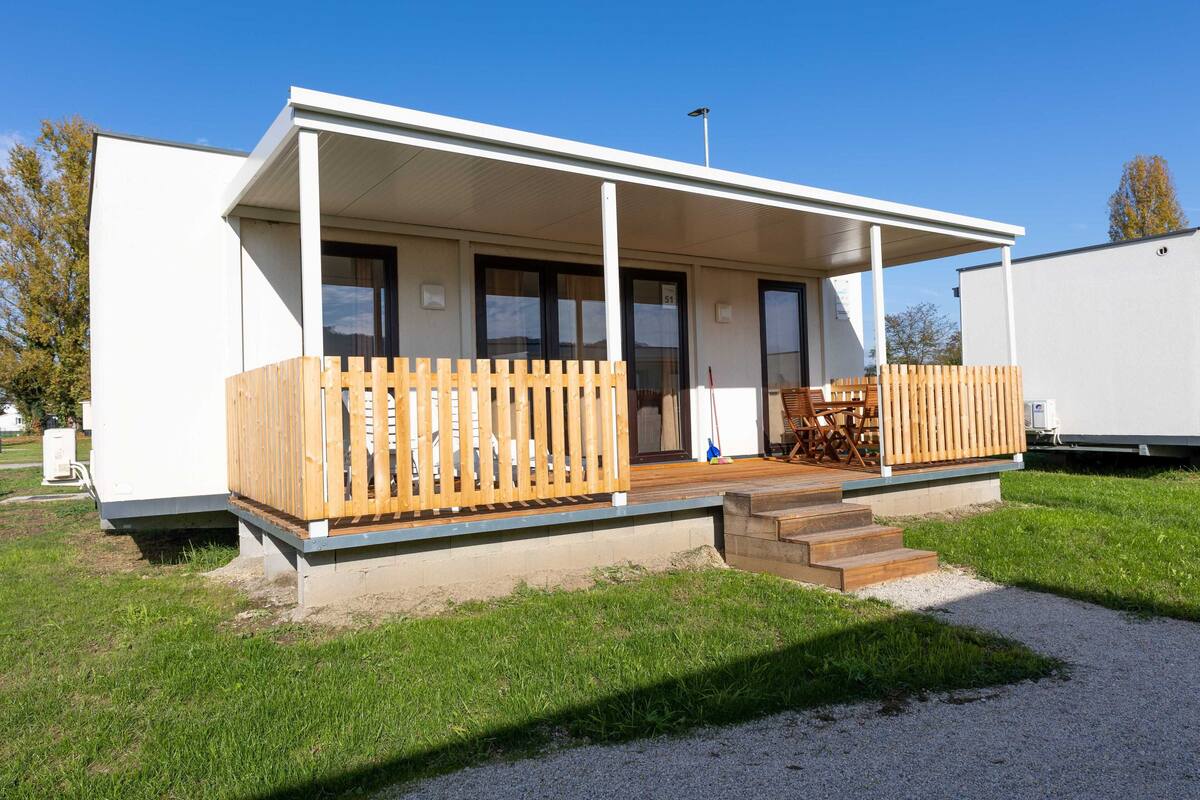 Een modern, laag gebouw met een overdekte veranda, een houten omheining en een grindpad.
