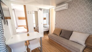 Een kleine kamer met een wit bureau, een beige bank en een houten vloer.