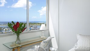 Ein Zimmer mit großem Fenster und Blick auf einen Jachthafen und das Meer.