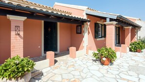 Un edificio con techo de tejas, paredes de ladrillo y plantas en macetas.