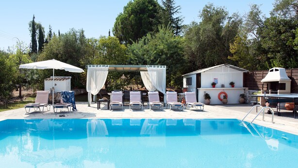 Una piscina con sillones de descanso y una sombrilla.