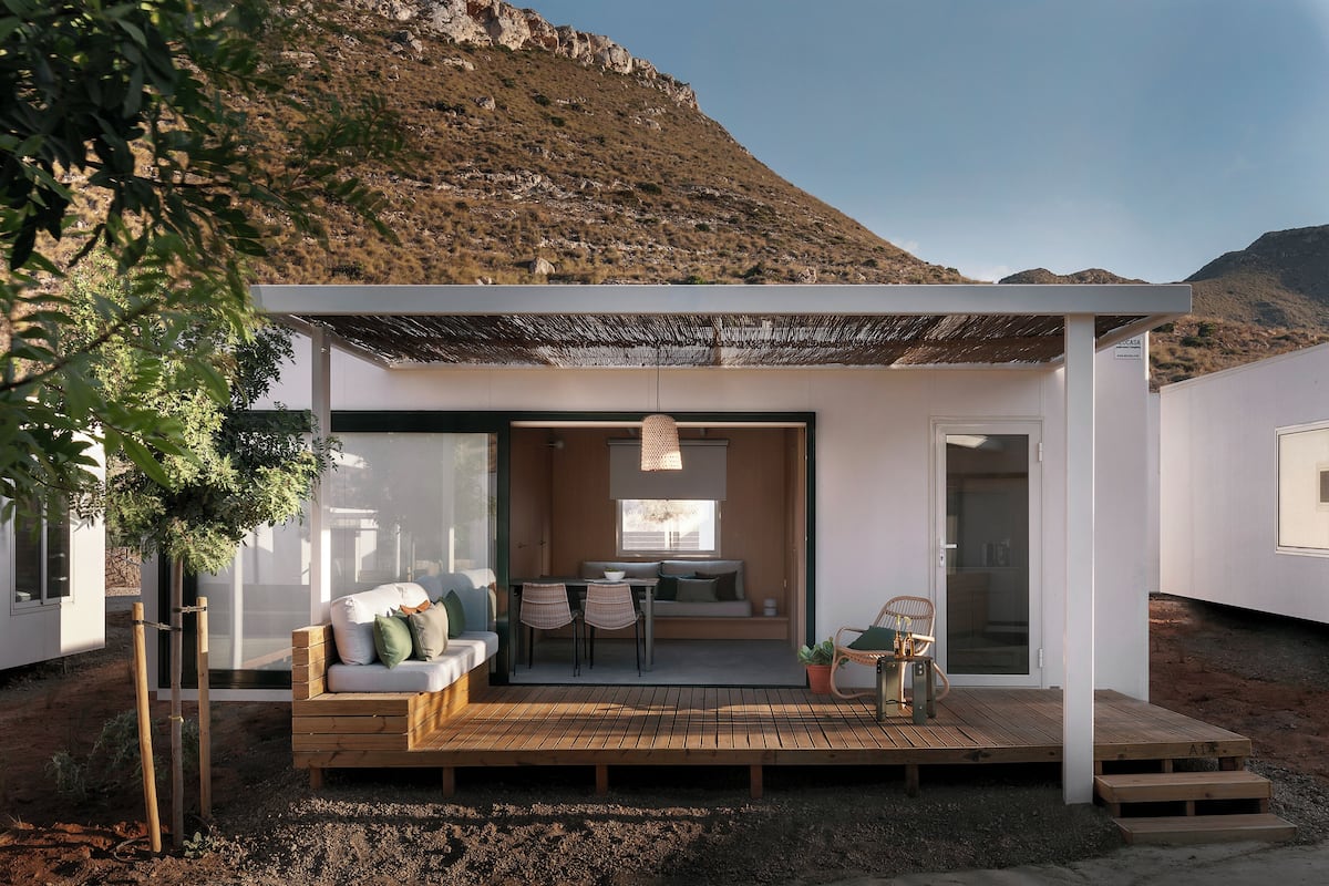 A modern outdoor living area with a wooden deck, seating, and a covered patio.