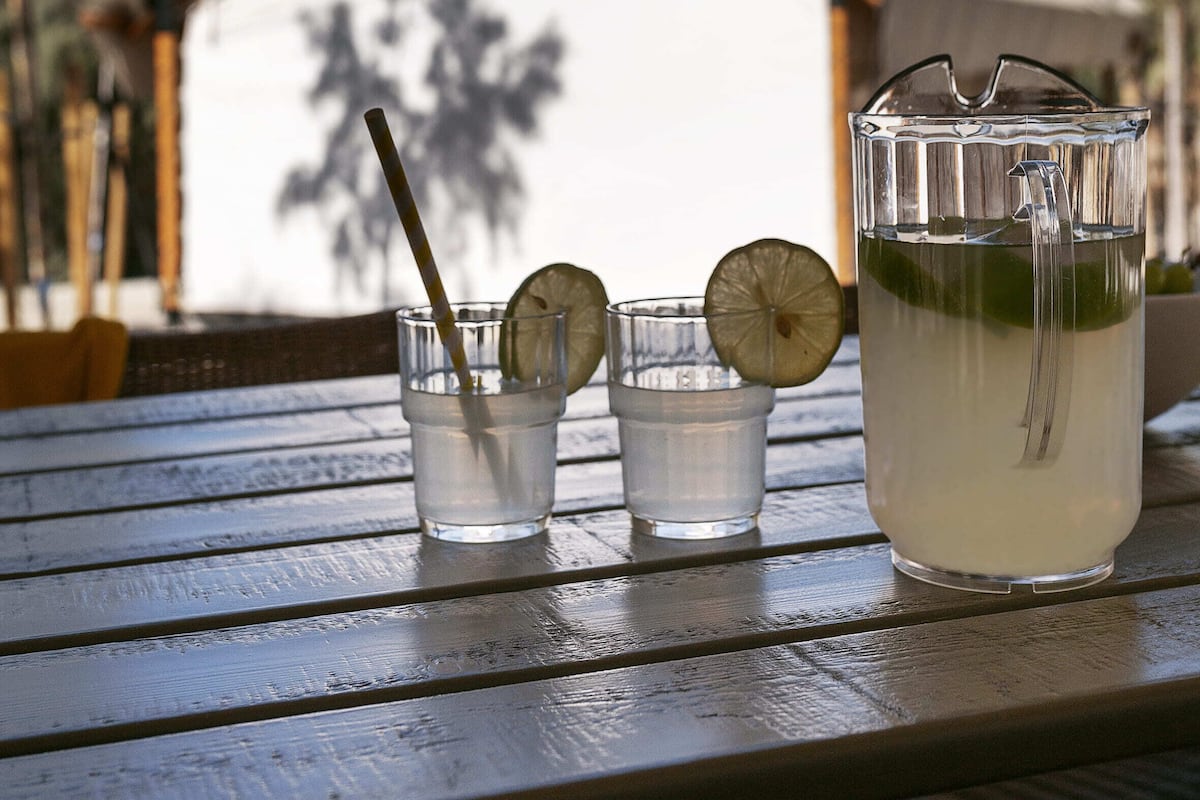 A table with a glass pitcher, two small glasses, and a straw.