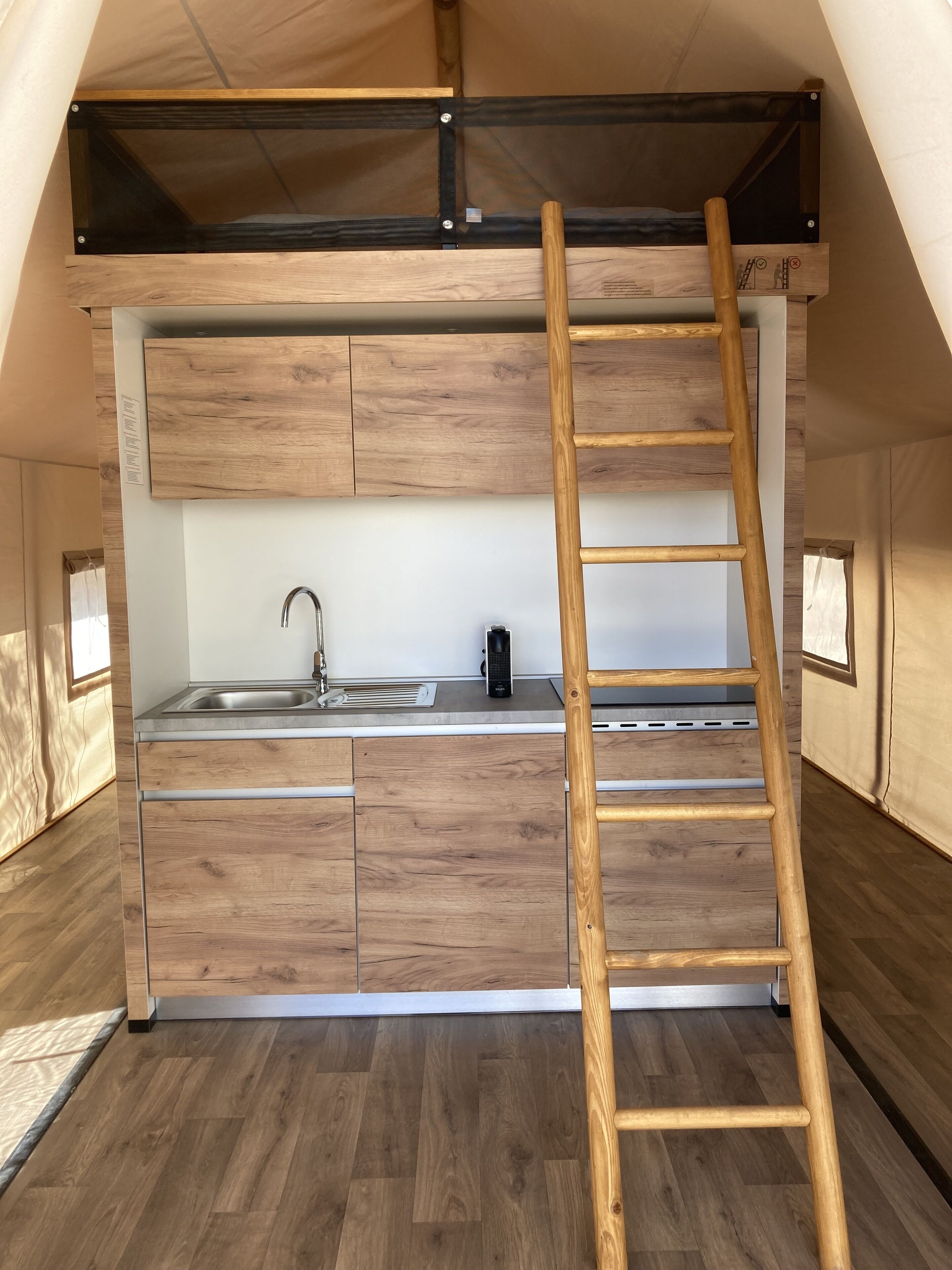 Een kleine keuken met een houten aanrecht, een spoelbak en een trap.