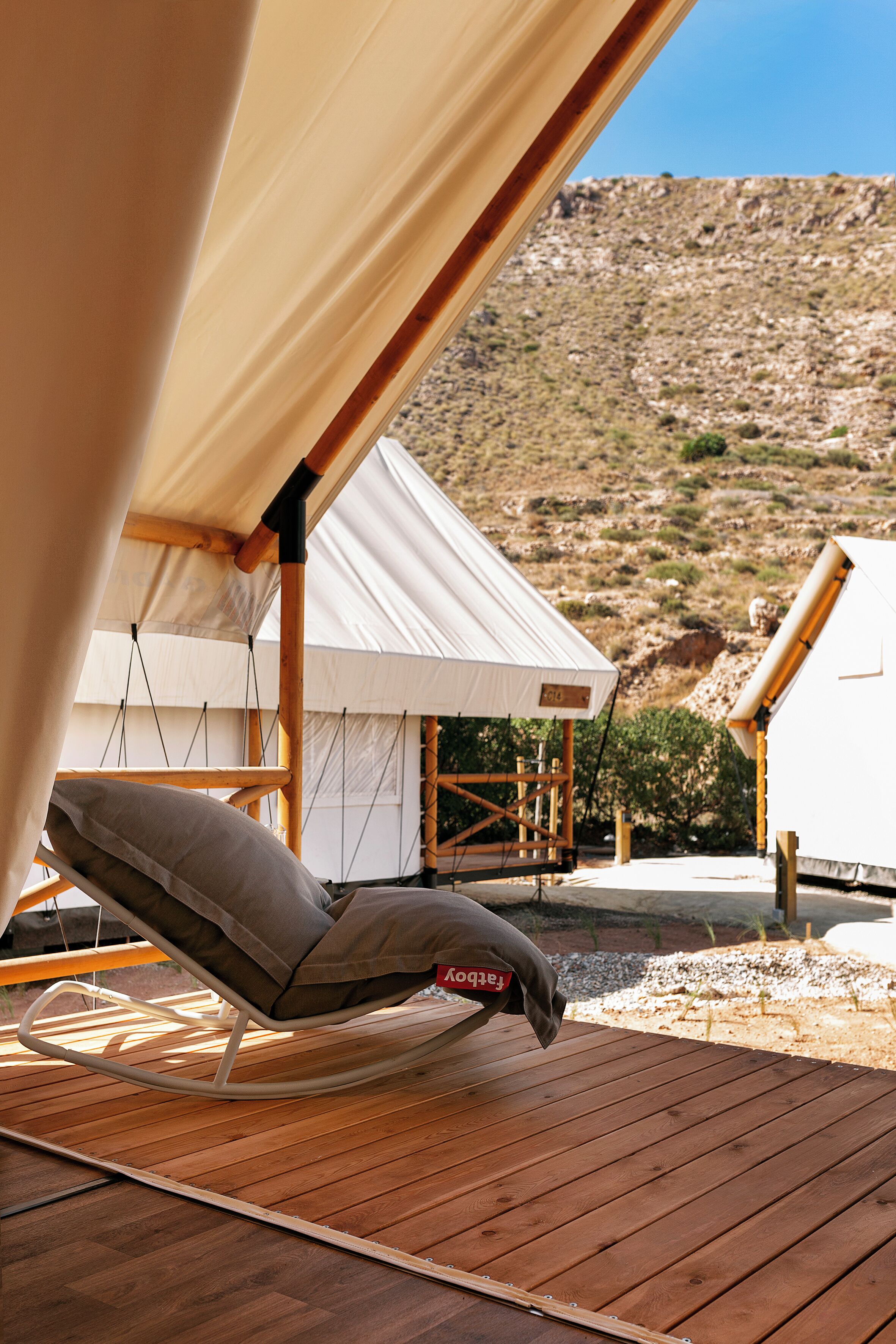 A wooden deck with a rocking chair and a tent structure.