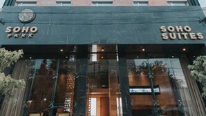 Et højt hotel med moderne design, der har en markant indgang med glasdøre og siddepladser udendørs.