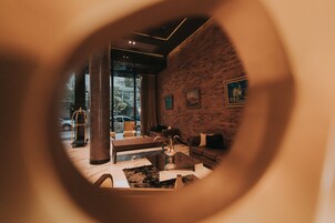 Un interior moderno con una mesa de centro de vidrio, sofá de cuero y pared de ladrillo con fotografías enmarcadas.