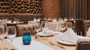En restaurant med dækkede borde, en dekorativ væg og et mønstret loft.