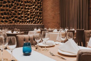 Un ambiente de restaurante con mesas listas para comer, que presenta una pared decorativa y un techo con diseño.