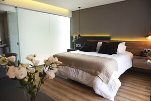 Un dormitorio moderno con una cama grande, mesitas de noche y un jarrón con flores.