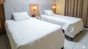 Une chambre d’hôtel avec deux lits, un mur à motifs et un rideau.