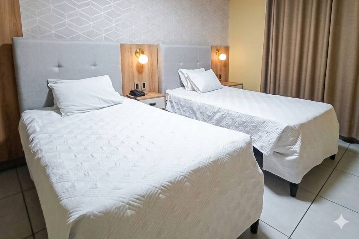 Une chambre d’hôtel avec deux lits, un mur à motifs et un rideau.