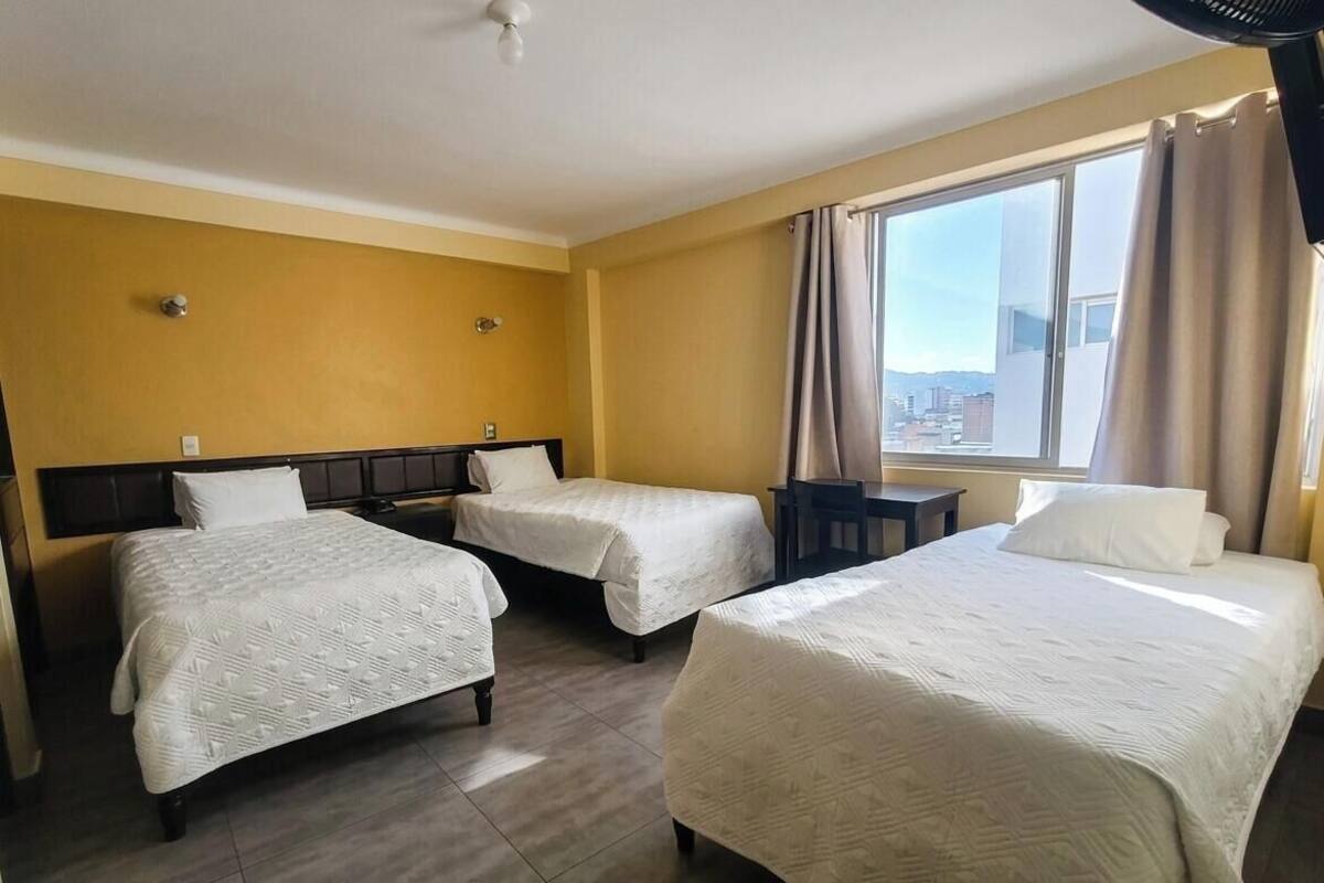 Une chambre d’hôtel avec deux lits, une fenêtre avec des rideaux et une vue sur la ville.