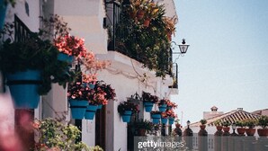 A narrow street with buildings on either side, each with balconies adorned with potted plants and flowers. - Design villa in Cala de Mijas (La Cala de Mijas)