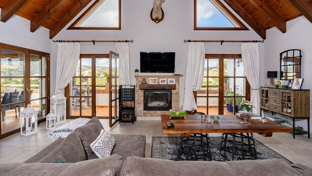 A spacious living room with a fireplace, a television, and a dining area with a table and chairs. - Design villa in Cala de Mijas (La Cala de Mijas)