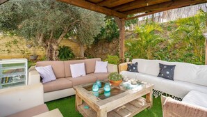 An outdoor patio with a wooden pergola, two sofas, a coffee table, and various plants. - Design villa in Cala de Mijas (La Cala de Mijas)