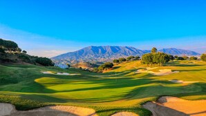 A golf course with sand bunkers, trees, and a mountain in the background. - Design villa in Cala de Mijas (La Cala de Mijas)