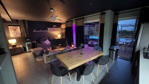 Un salon moderne avec une table à manger en bois, des chaises noires, un canapé et un ventilateur de plafond.
