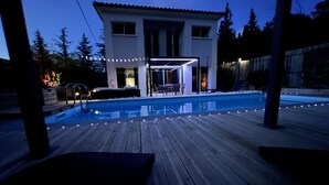 Une maison moderne dotée d’une piscine, d’une terrasse et d’un espace salon extérieur.