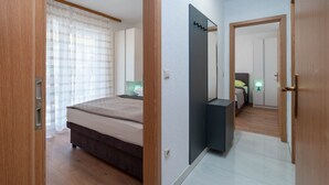 A bedroom with a bed, bedside tables, a mirror, and a door leading to another room.