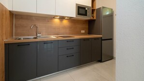 A modern kitchen with a wooden countertop, stainless steel appliances, and dark cabinetry.