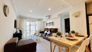 A modern living room with a sofa, a dining table set for two, and a large window with curtains. - South Apartment, in Torrecilla Nerja (Nerja)