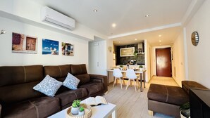 A modern living room with a brown sofa, a dining area with a white table and chairs, and a kitchen in the background. - South Apartment, in Torrecilla Nerja (Nerja)