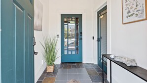 A teal door with a glass panel, a potted plant, and a framed map of Georgia on the wall.