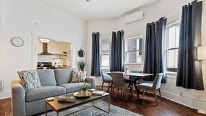 A modern living room with a grey sofa, a coffee table, and a dining area with a table and chairs.