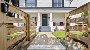 A wooden gate leading to a house with a front door and steps.