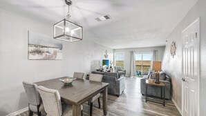 A dining area with a wooden table and chairs, a chandelier, and a painting on the wall.
