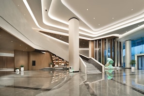 A modern lobby with a central staircase, a reception desk, and a large column. - Crowne Plaza Wuhan Optics Valley by IHG (Wuhan)