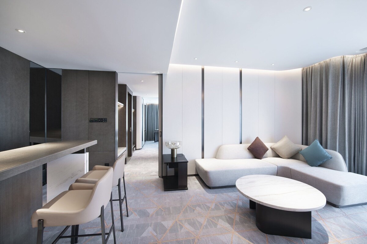 A modern living area with a sofa, a coffee table, and a bar area with stools.