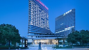 Un hotel moderno con fachada curva, varios balcones y una señalización destacada.