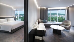 Habitación de hotel moderna con una cama grande, un sofá, una mesa de centro y vistas a la ciudad.