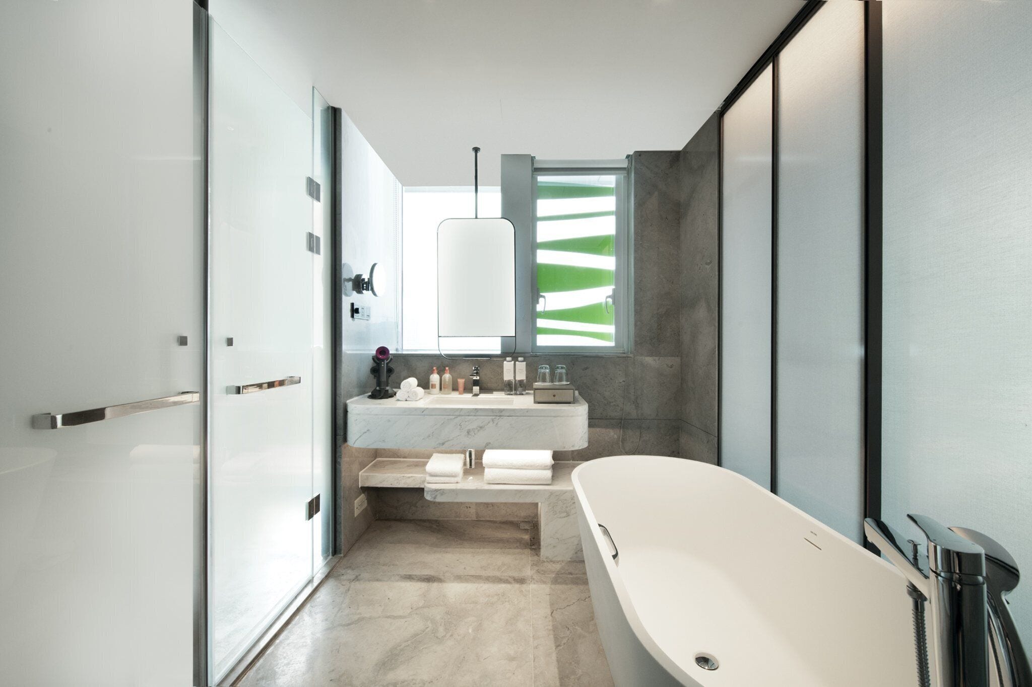 A modern bathroom with a freestanding bathtub, a large mirror, and a vanity with a marble countertop.