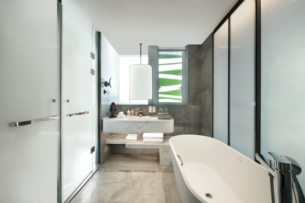 A modern bathroom with a freestanding bathtub, a vanity with a mirror, and a shower area.
