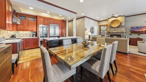 A modern kitchen with wooden cabinets, stainless steel appliances, and a dining area with a marble table.
