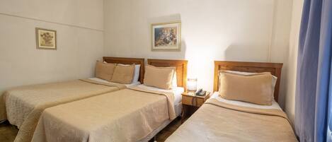 Una habitación de hotel con dos camas individuales, una mesita de noche con teléfono y un cuadro en la pared.