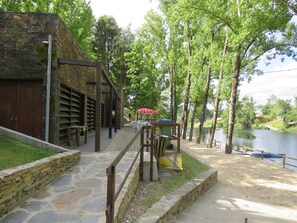 A stone building with a wooden deck and a river view.